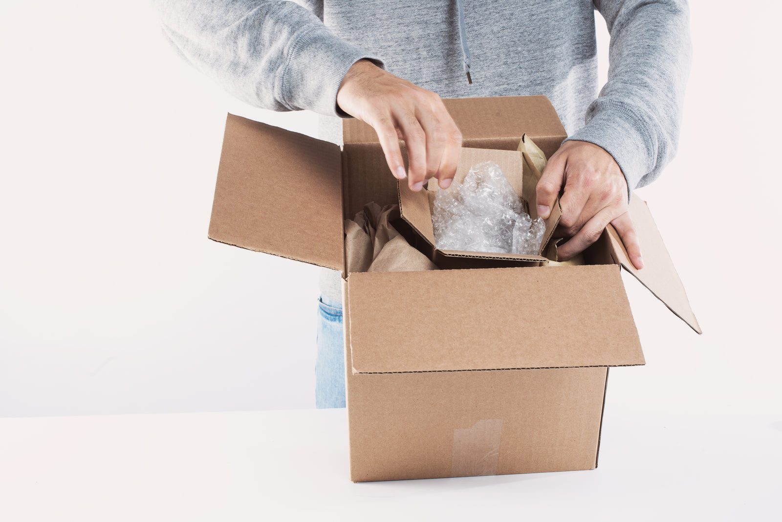 Manos alistando un pedido dentro de una caja