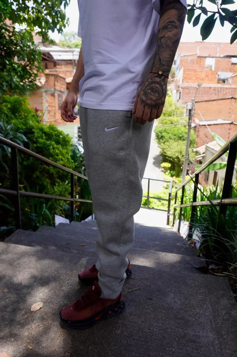 Hombre sentado en la calle con jogger gris y tenis negros
